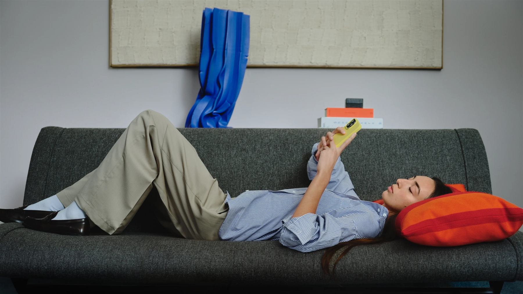A woman lying on a sofa, looking at her phone